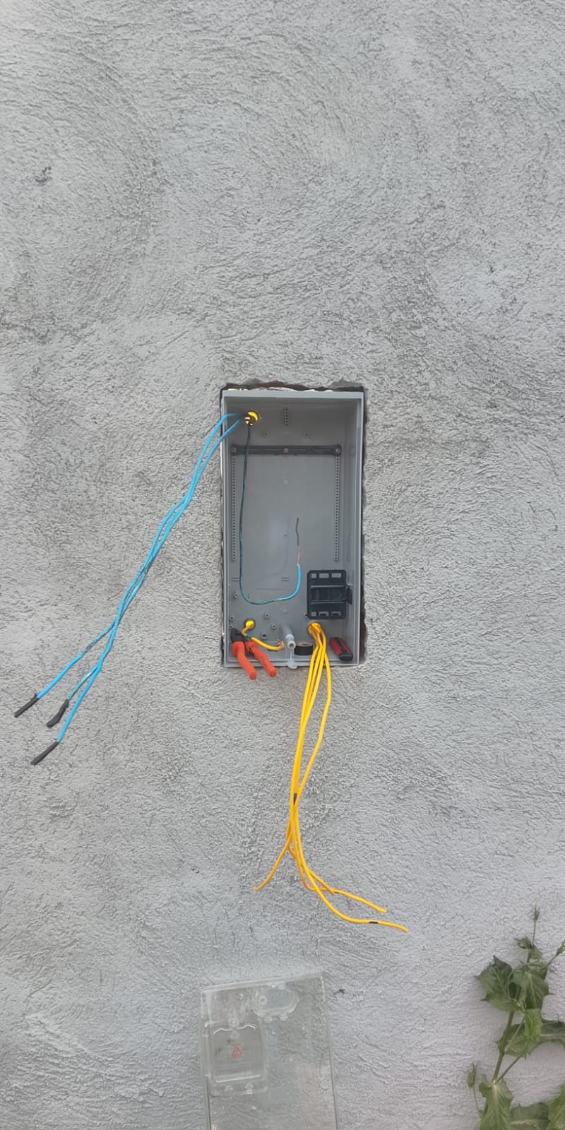 Quadro de distribuição elétrico em instalação em parede externa, com fiação azul e amarela passada.