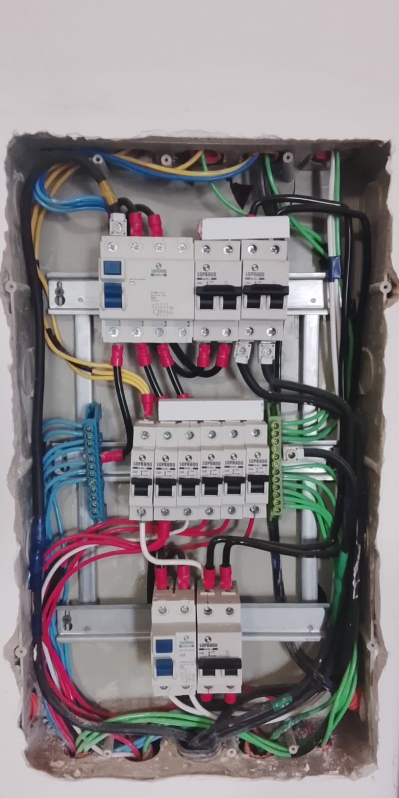 Painel elétrico residencial novo com disjuntores Soprano e fiação organizada por cor, mostrando serviço de instalação/troca de padrão.